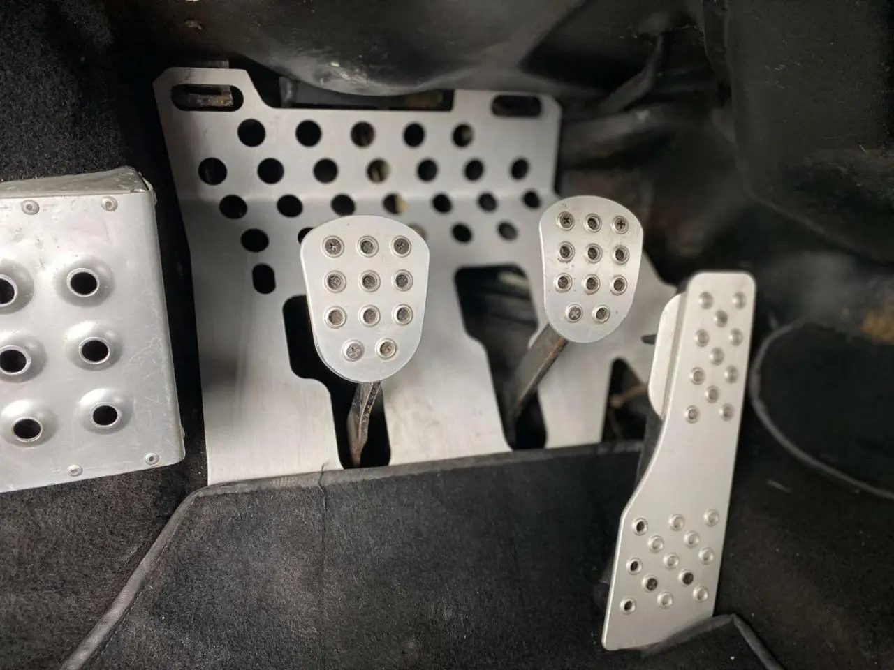 Gros plan sur les pédales en aluminium perforé de la Porsche 911 3.0 SC 930 Kg homologuée route, intérieur noir.