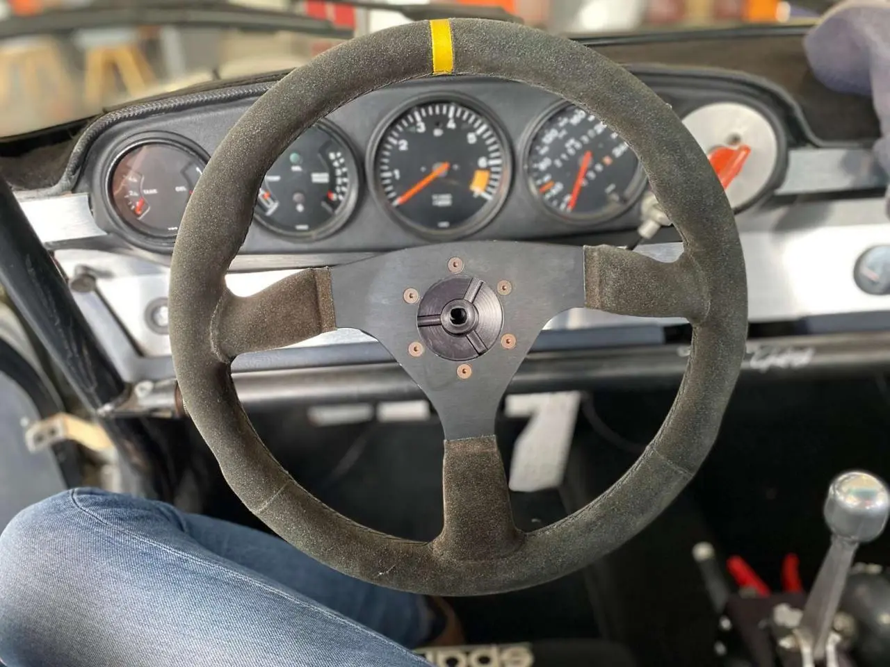 Vue intérieure centrée sur le volant Sparco en alcantara et le tableau de bord de la Porsche 911 3.0 SC gris métallisé.