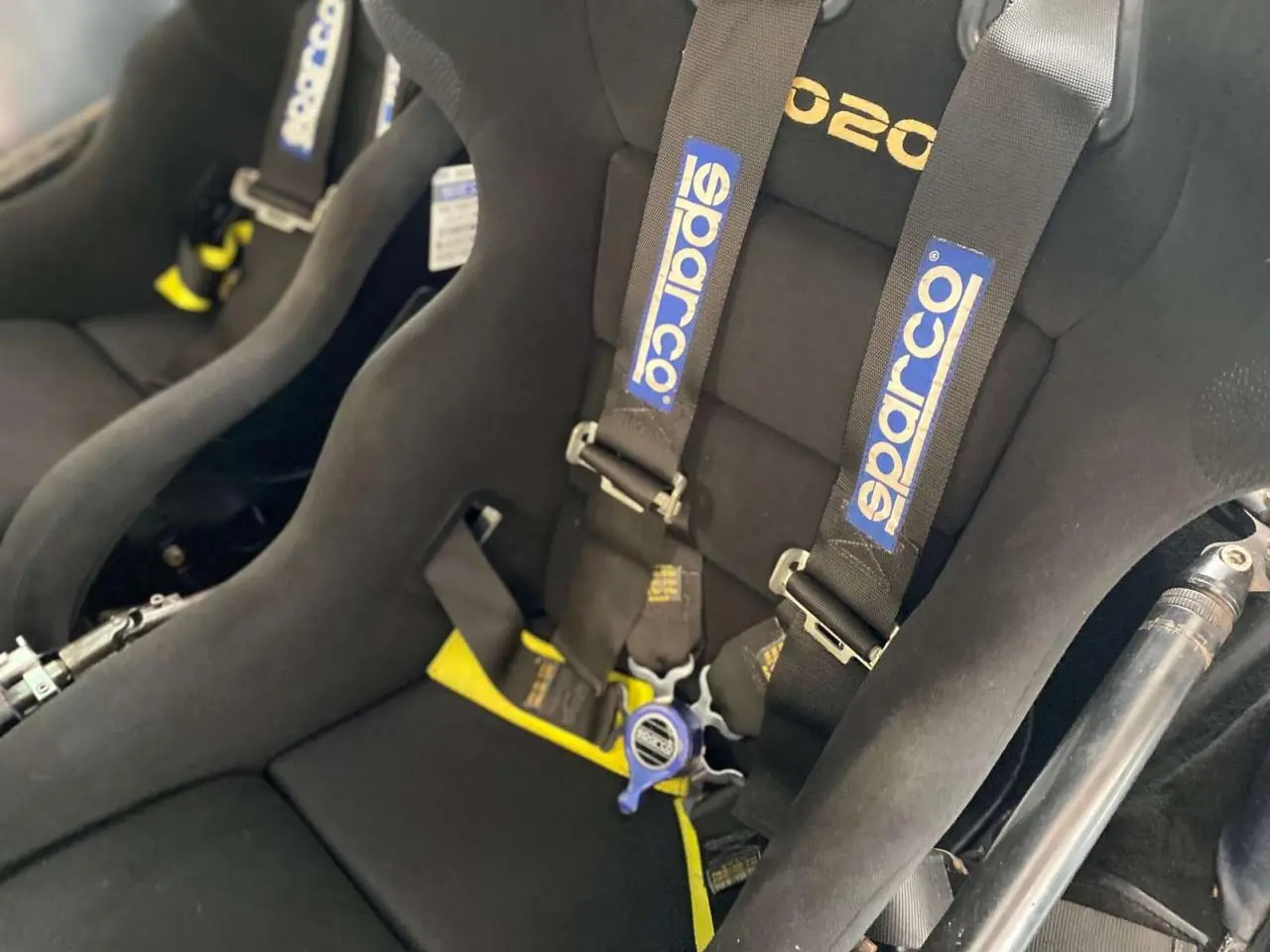 Gros plan sur les baquets Sparco noirs avec harnais 6 points dans l’habitacle d’une Porsche 911 3.0 SC gris métallisé.