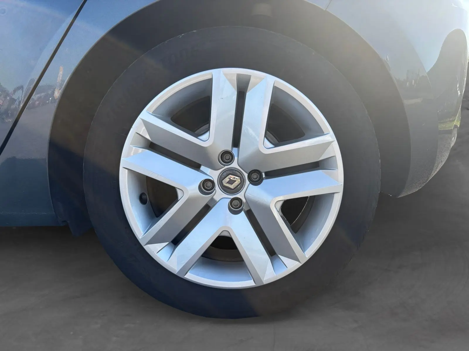 Gros plan sur la roue avant droite d'une Renault Clio gris foncé, mettant en valeur la jante alliage au design moderne.