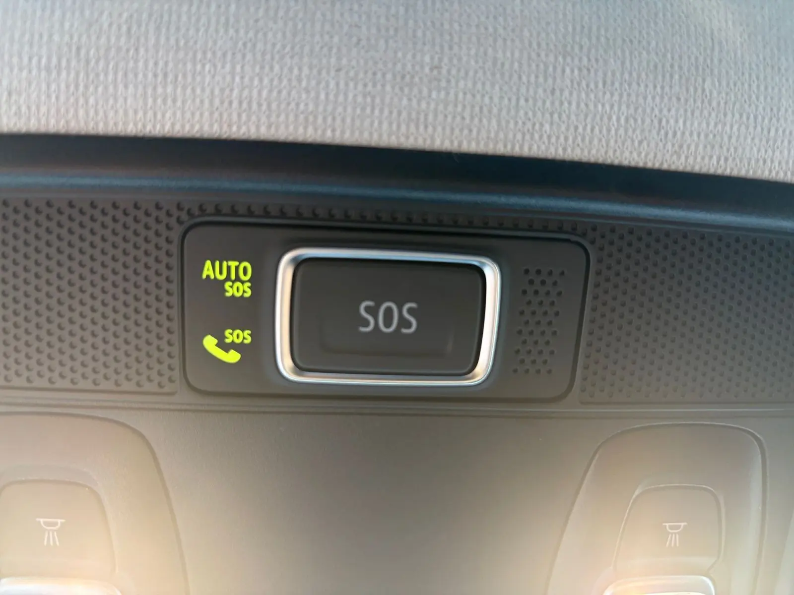 Bouton SOS lumineux sur le plafonnier intérieur de la Renault Clio gris foncé, vue en gros plan.