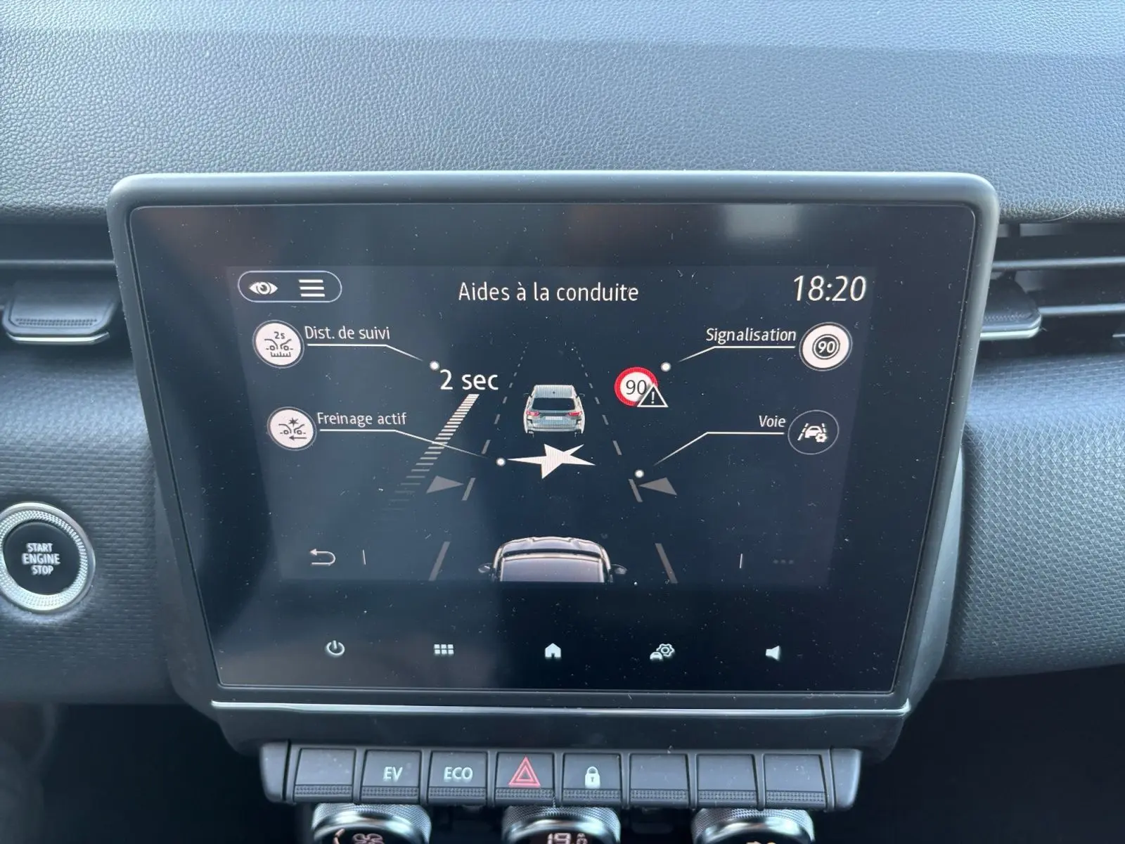Écran tactile central de la Renault Clio 1.6 E-TECH Business 2021 montrant les aides à la conduite, bouton start/stop visible.