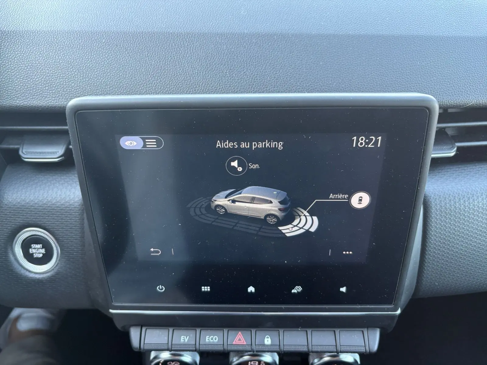 Écran tactile central d’une Renault Clio 1.6 E-TECH Business 2021 affichant l’aide au parking, avec bouton Start/Stop visible à gauche.
