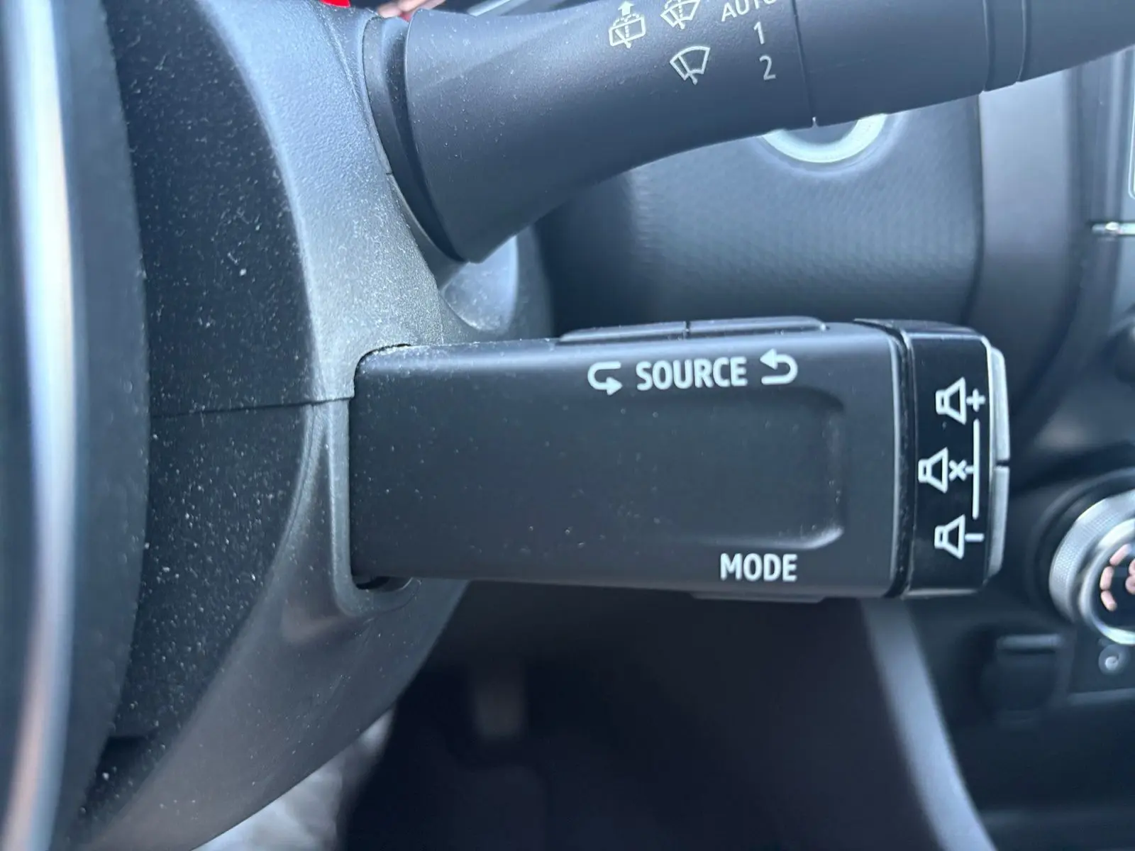 Gros plan sur la commande au volant droite de la Renault Clio gris foncé 2021, avec boutons source et mode visibles.