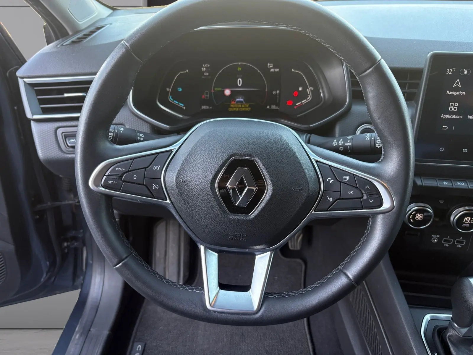Vue rapprochée du volant noir de la Renault Clio gris foncé 2021, avec tableau de bord digital et commandes intégrées.