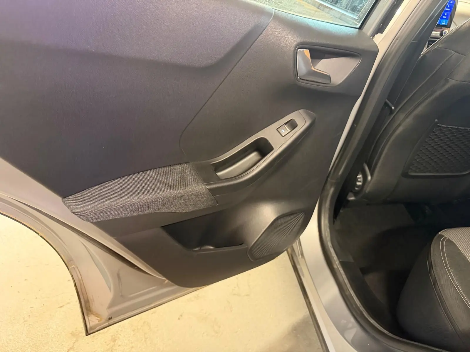 Vue rapprochée de la porte arrière droite grise du Ford Puma 2021, avec garniture noire et tissu gris.