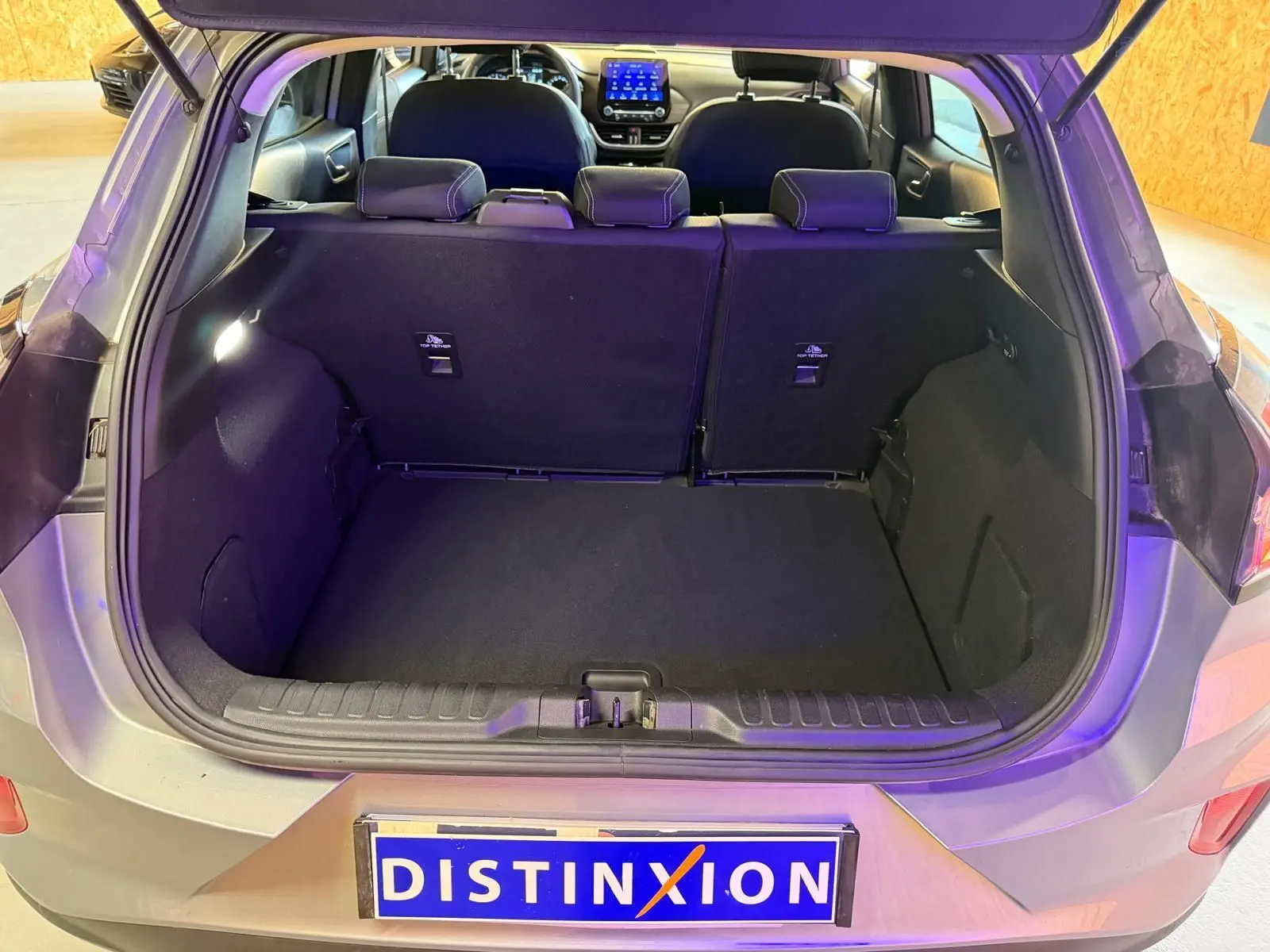 Vue arrière du coffre ouvert d'un Ford Puma gris 2021, montrant l'intérieur spacieux et les sièges arrière rabattables.