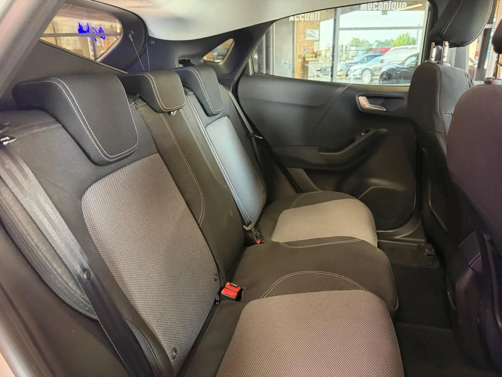 Vue intérieure côté droit des sièges arrière en tissu noir et gris du Ford Puma 2021 gris, avec appuie-têtes et ceintures visibles.