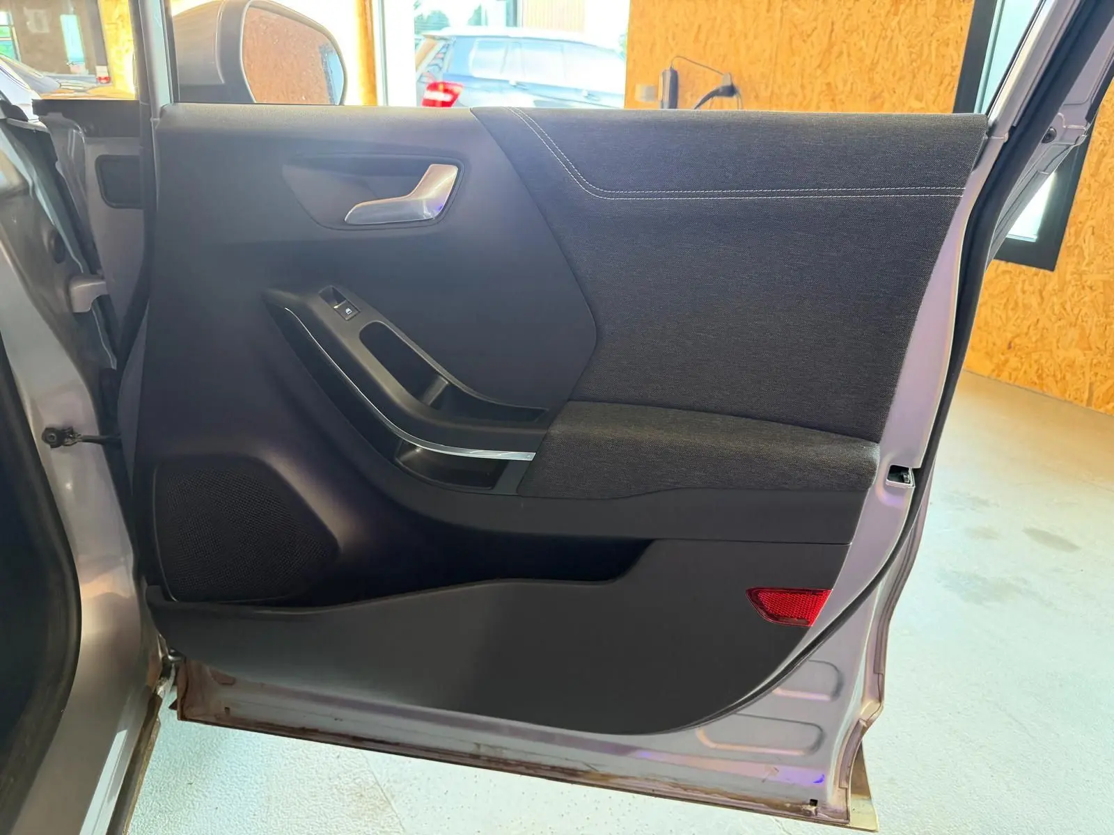 Vue intérieure côté gauche de la porte arrière grise du Ford Puma 2021 avec garniture tissu noir et poignée argentée.