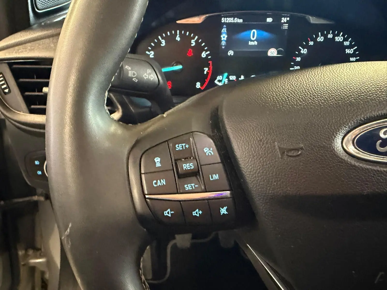 Gros plan sur le volant noir et le tableau de bord digital du Ford Puma gris 2021, avec commandes au volant visibles.
