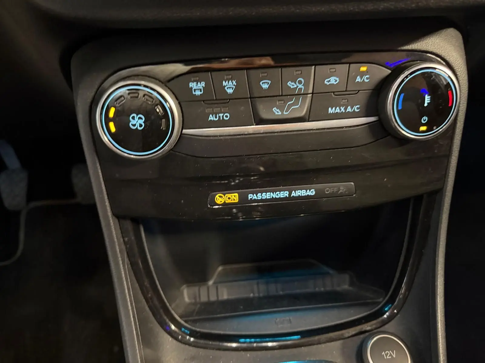 Vue rapprochée de la console centrale du Ford Puma gris 2021, montrant les commandes de climatisation et l'indicateur d'airbag passager.