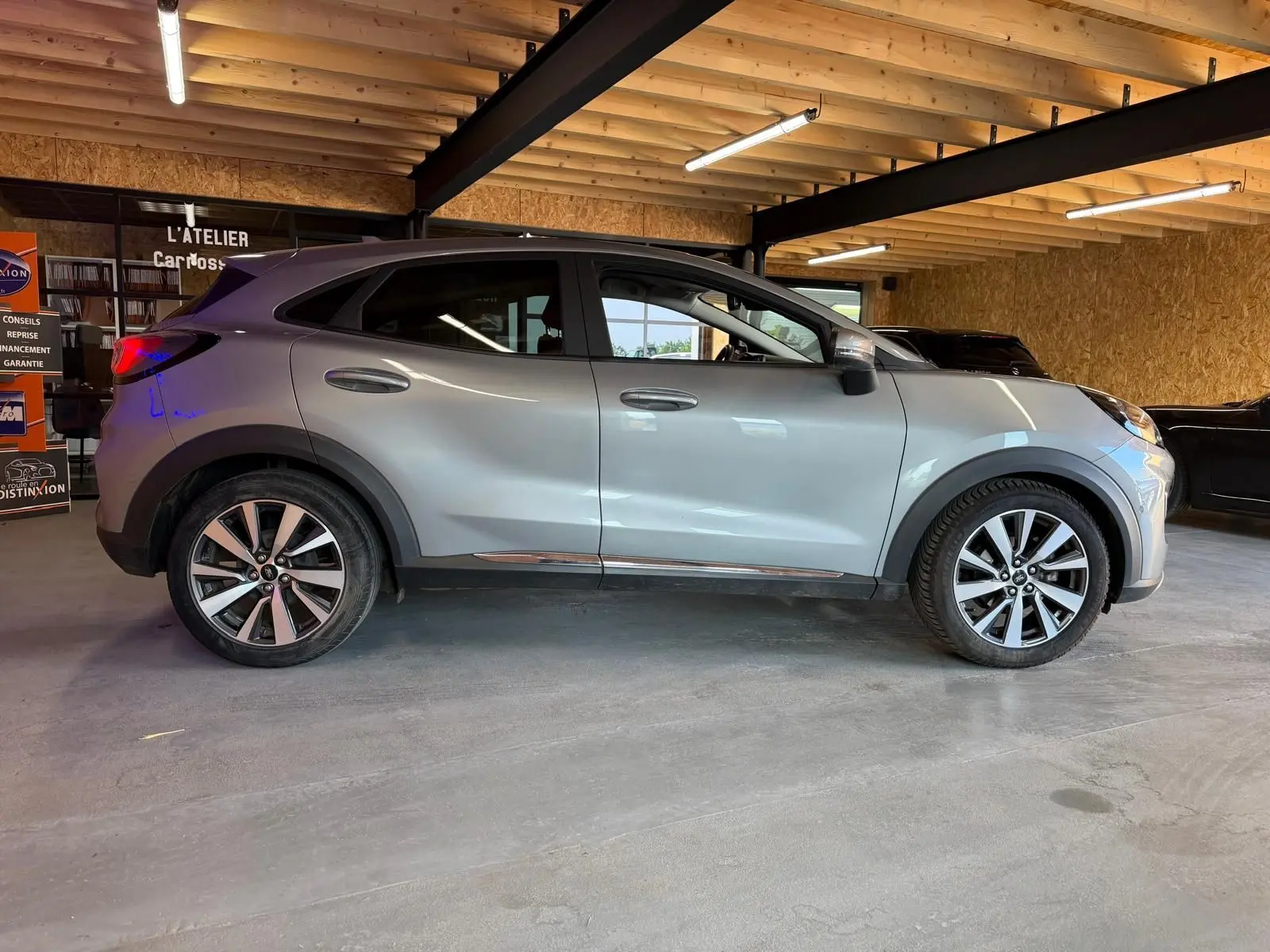 Vue latérale gauche d'un Ford Puma gris 2021 en intérieur, soulignant ses jantes alliage et lignes modernes.