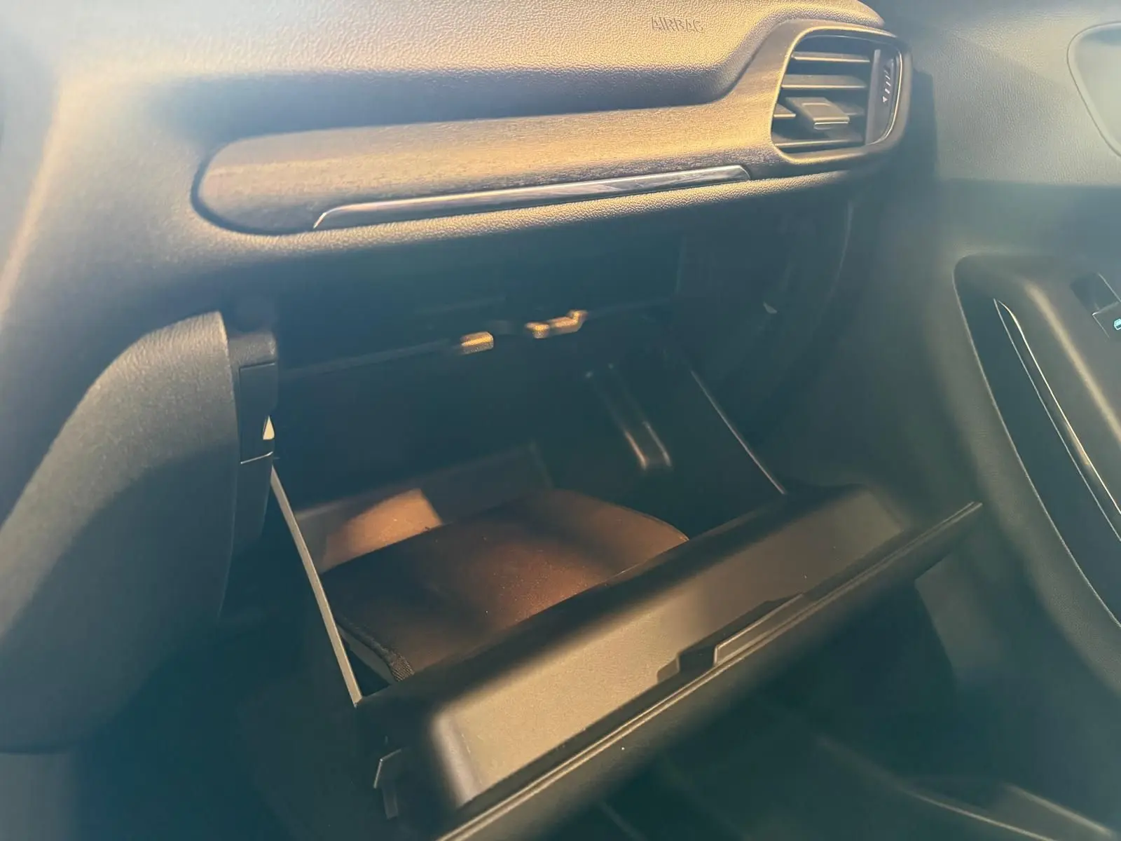Vue rapprochée de la boîte à gants ouverte côté passager de l’intérieur noir du Ford Puma gris 2021.
