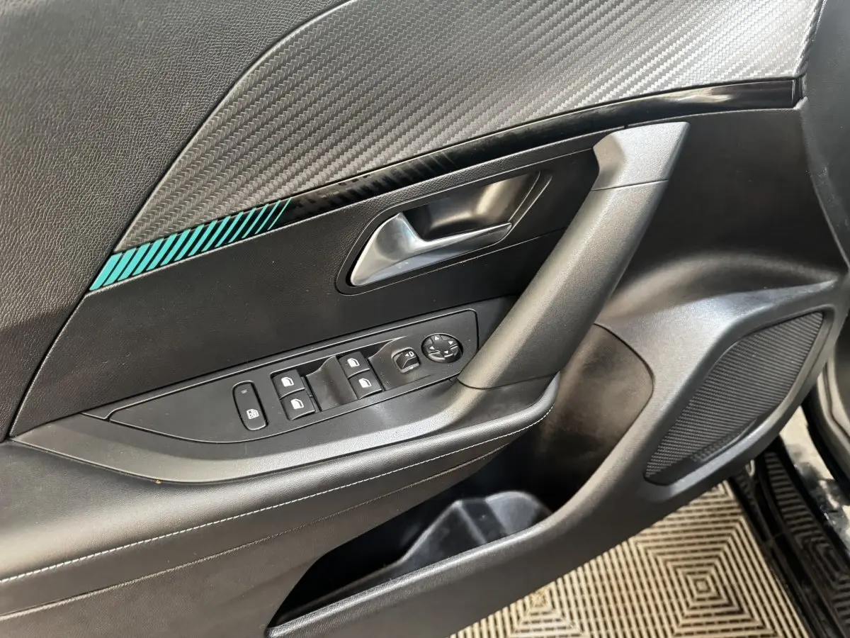 Détail de la porte avant gauche noire du Peugeot 2008 avec commandes des vitres et insert décoratif bleu.