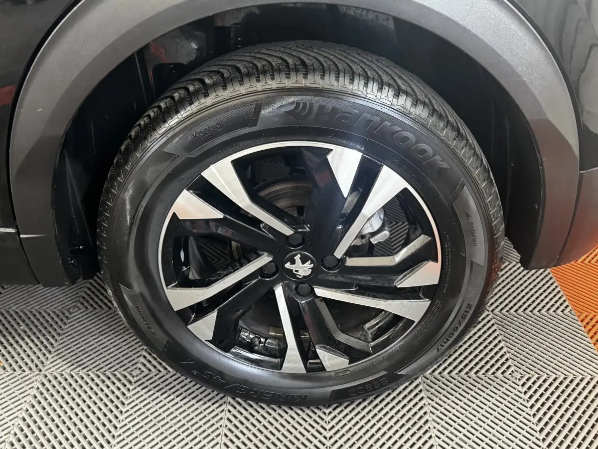 Gros plan sur la roue avant droite noire d’un Peugeot 2008 2022 avec jante alliage bicolore et pneu Hankook.