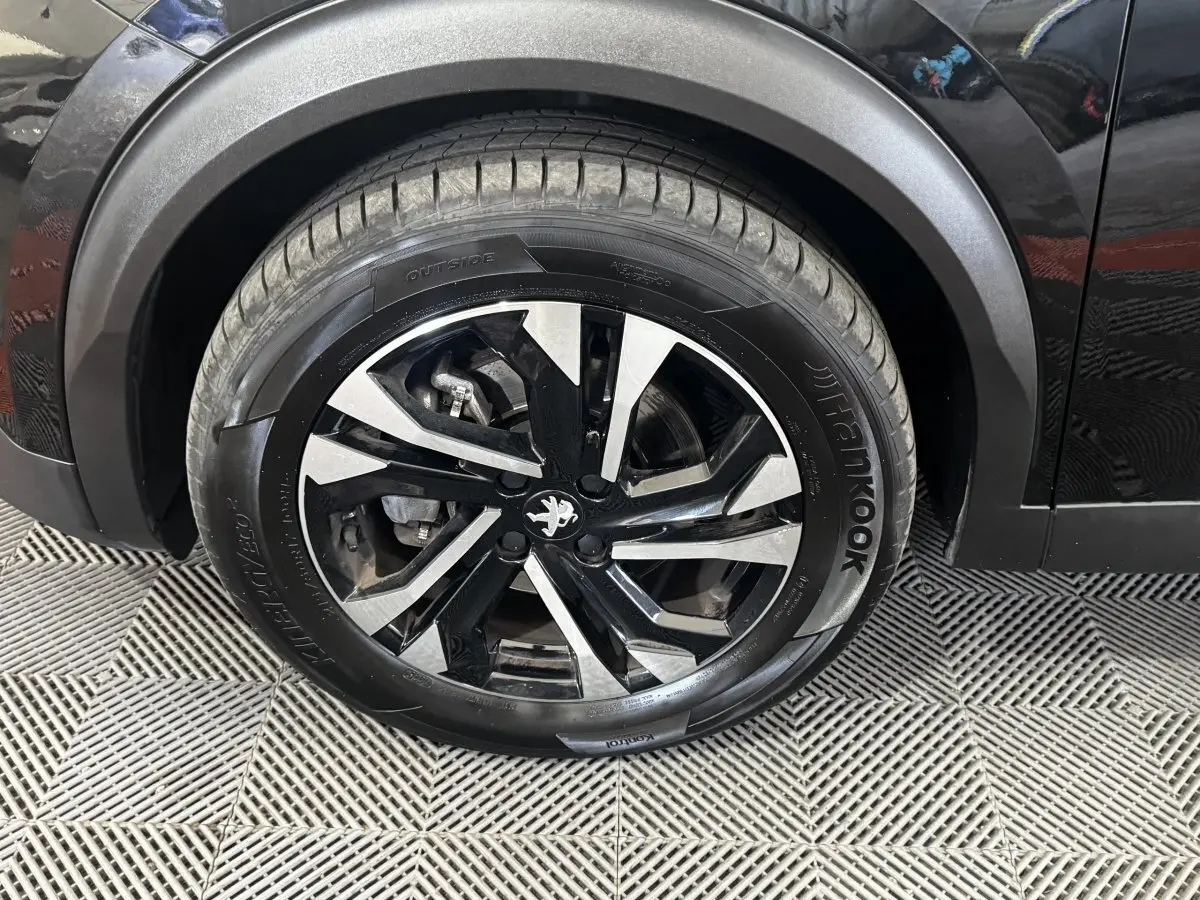 Gros plan sur la roue avant droite noire avec jante alliage bicolore du Peugeot 2008 noir 2022.
