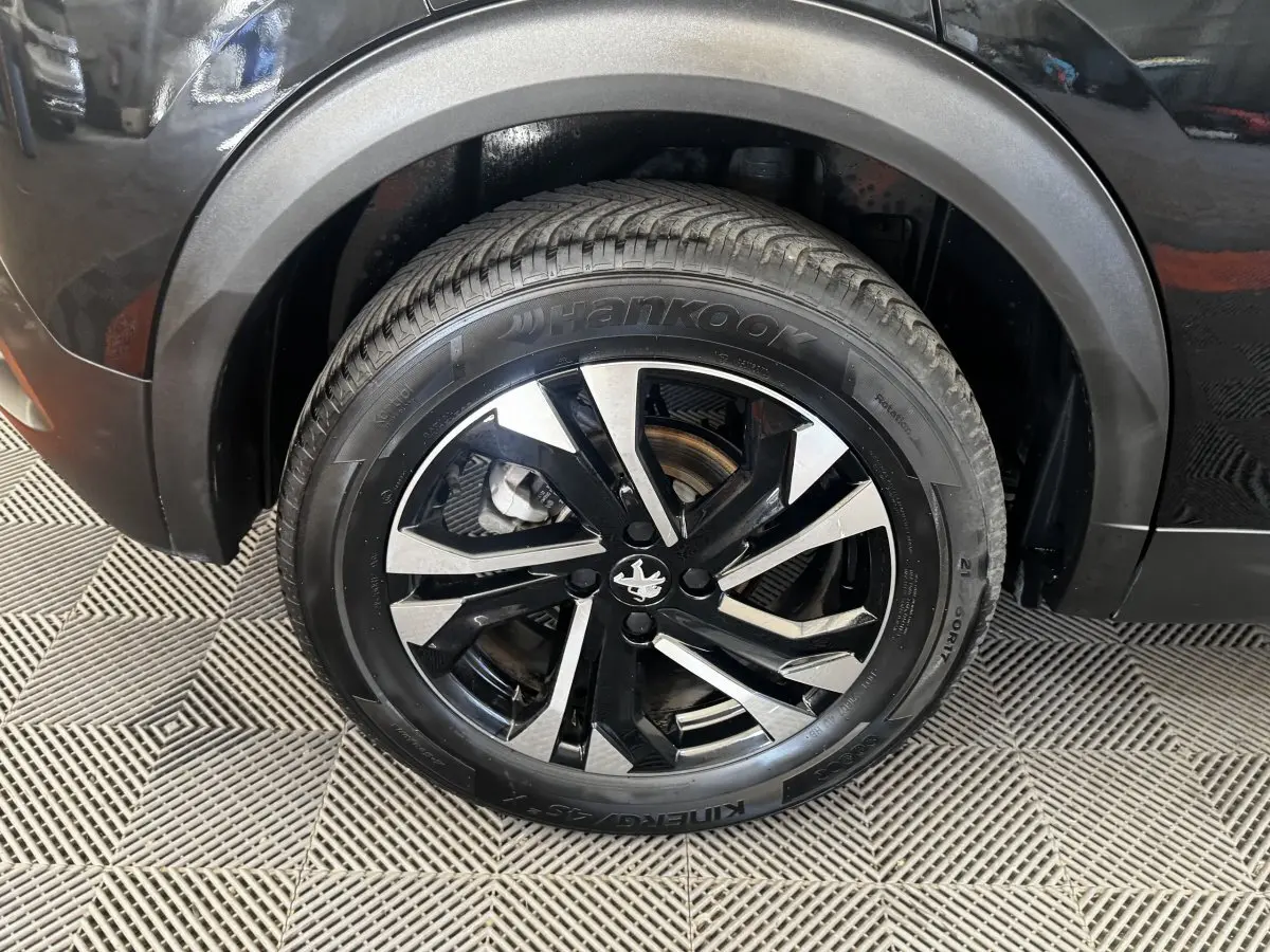 Gros plan sur la roue avant droite noire avec jante alliage bicolore du Peugeot 2008 noir 2022.