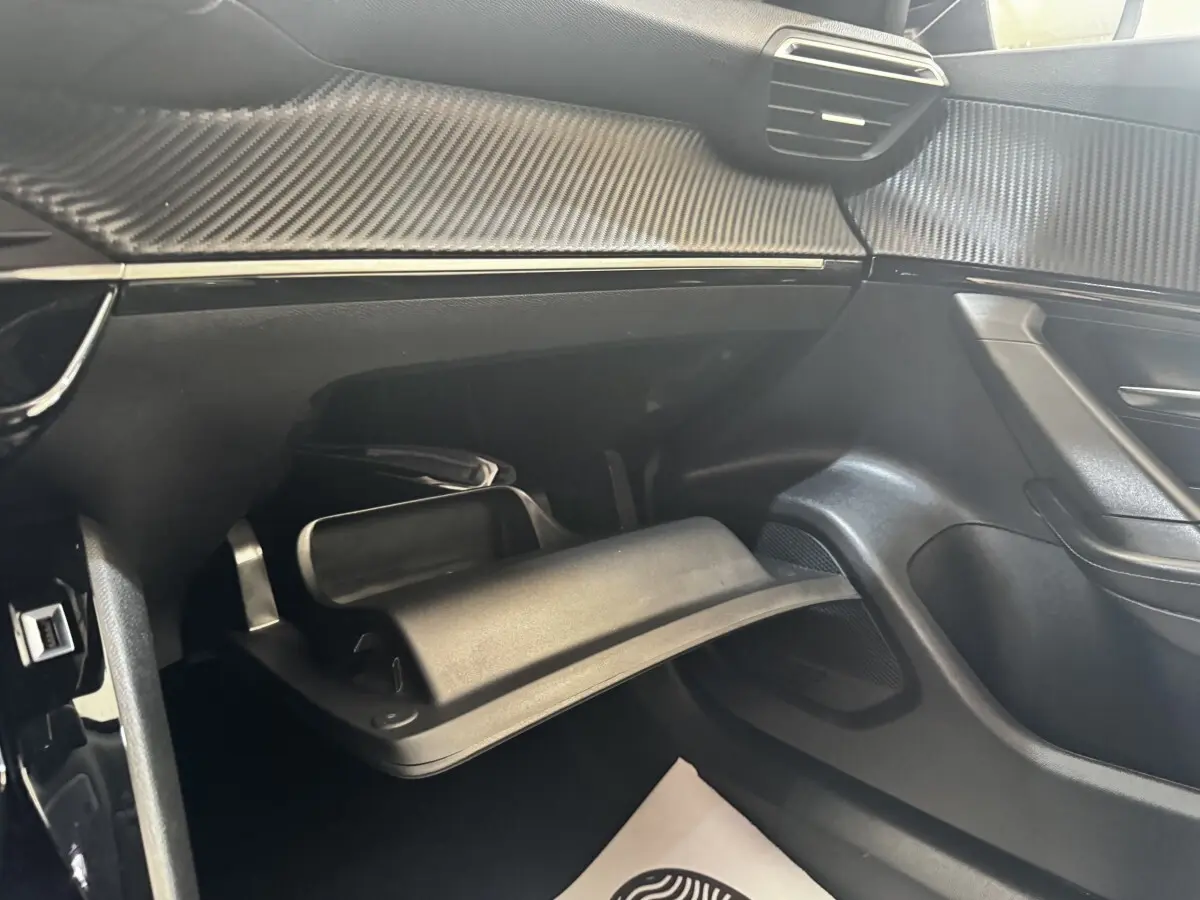 Intérieur côté passager du Peugeot 2008 2022, vue sur la boîte à gants ouverte et le tableau de bord noir avec insert carbone.