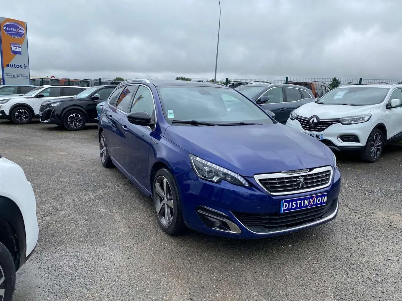 Peugeot 308 SW bleu magnétique vue 3/4 avant gauche sur parking avec calandre chromée et jantes alliage.