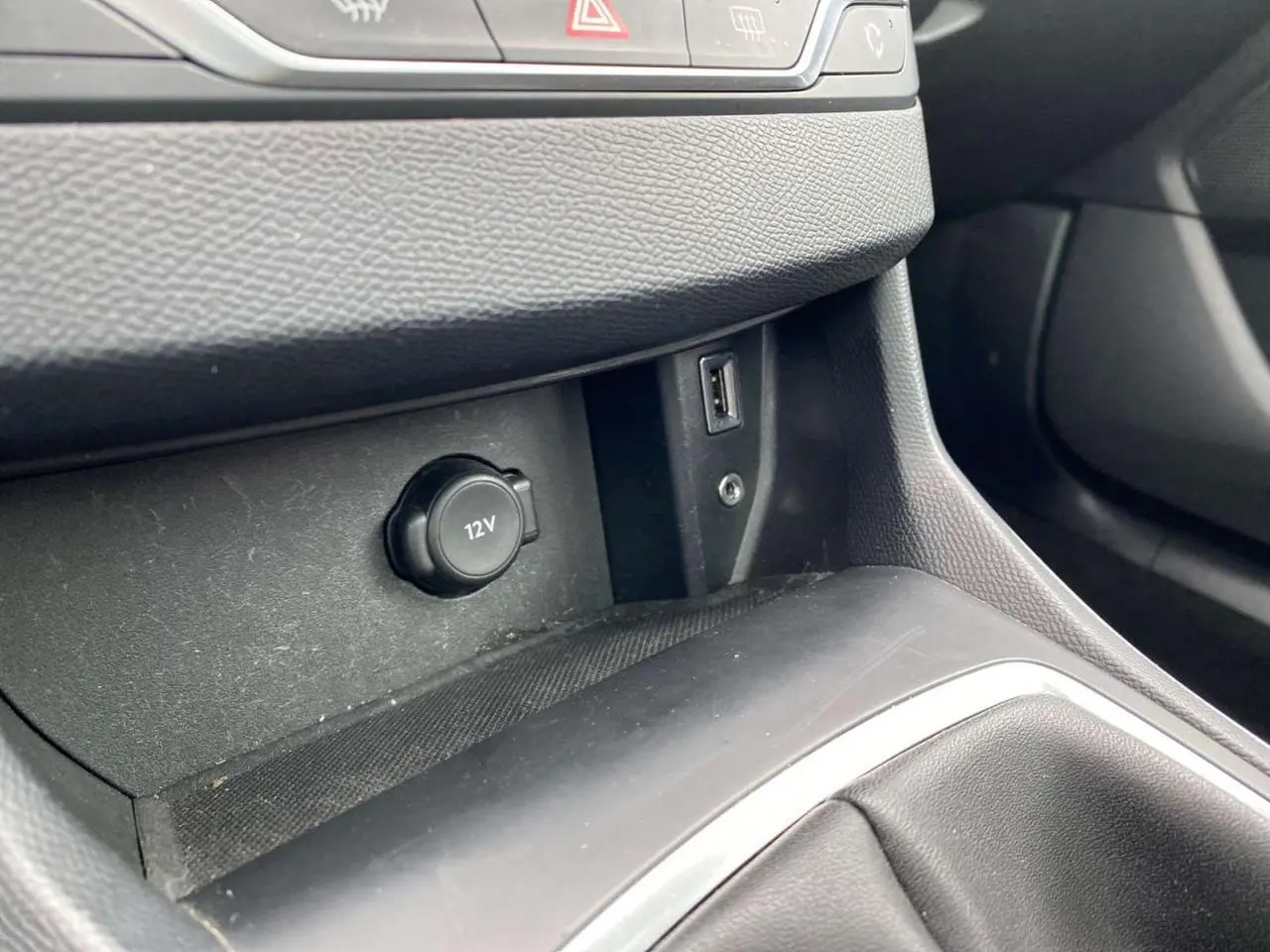 Gros plan sur la prise 12V et port USB dans la console centrale noire d'une Peugeot 308 SW 2017.