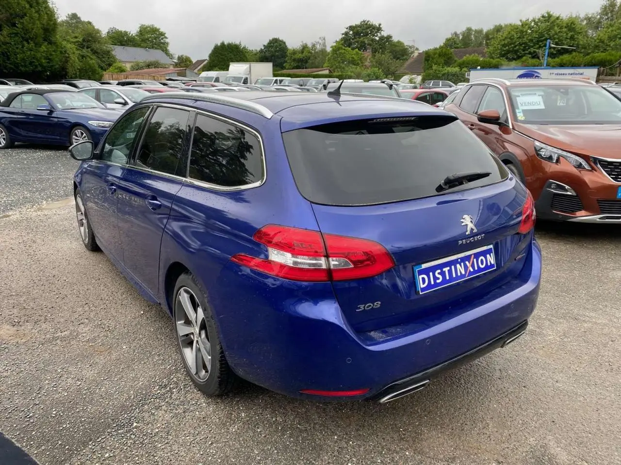 Vue 3/4 arrière droite d'une Peugeot 308 SW bleu magnétique avec feux arrière LED et double sortie d'échappement chromée.