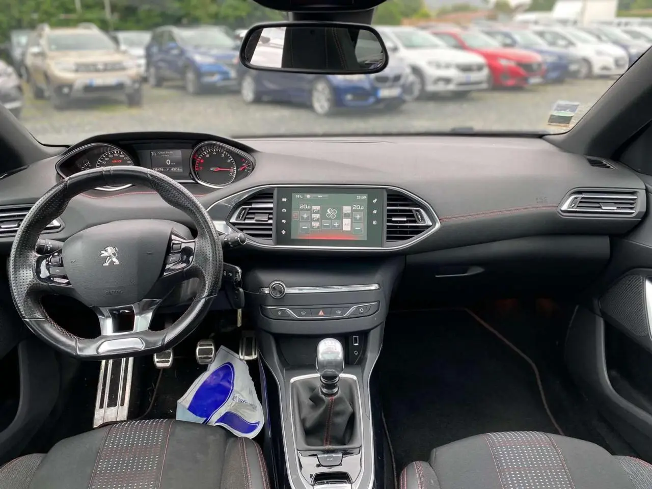 Intérieur de la Peugeot 308 SW 2017 avec tableau de bord noir, volant cuir perforé et console centrale avec écran tactile.