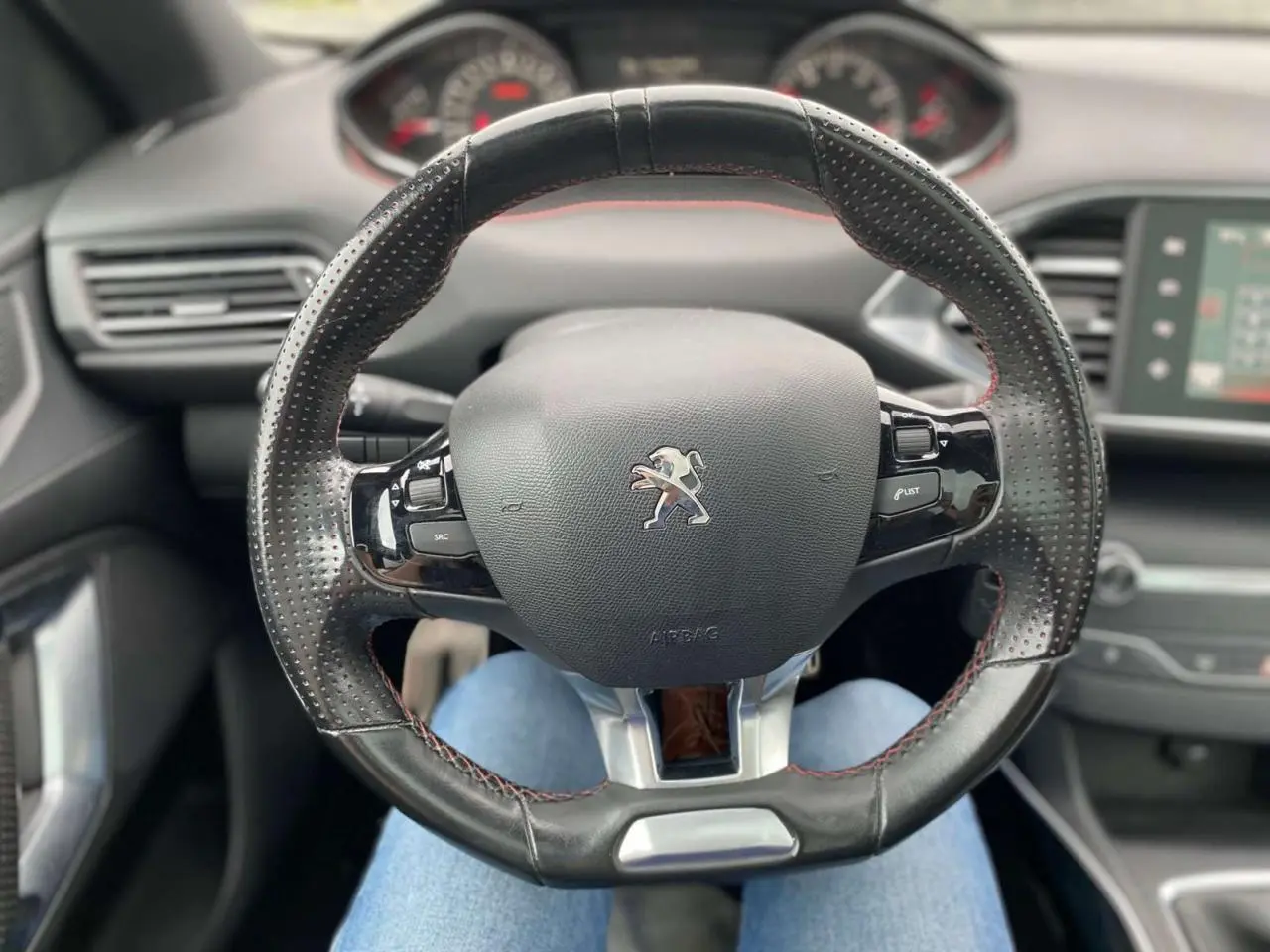 Volant cuir noir à surpiqûres rouges de la Peugeot 308 SW GT Line 2017, vue centrée sur le poste de conduite.