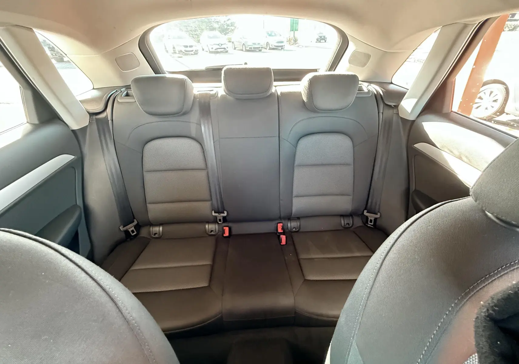 Vue intérieure arrière montrant les sièges arrière noirs en tissu de l'Audi Q3 2016 avec trois appuie-têtes.