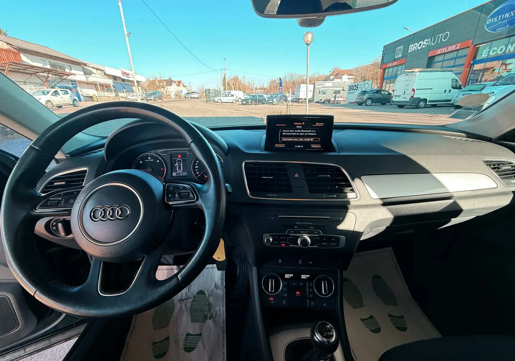 Vue intérieure de l'Audi Q3 2016 noir, montrant le tableau de bord, volant et levier de vitesses manuel.