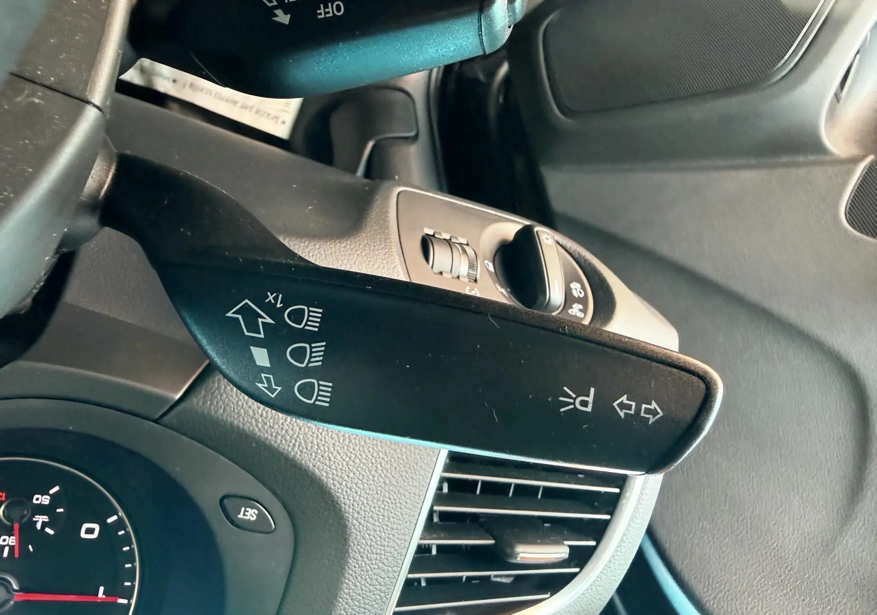Gros plan sur la manette de clignotant noire à gauche du volant dans l'habitacle d'un Audi Q3 noir de 2016.