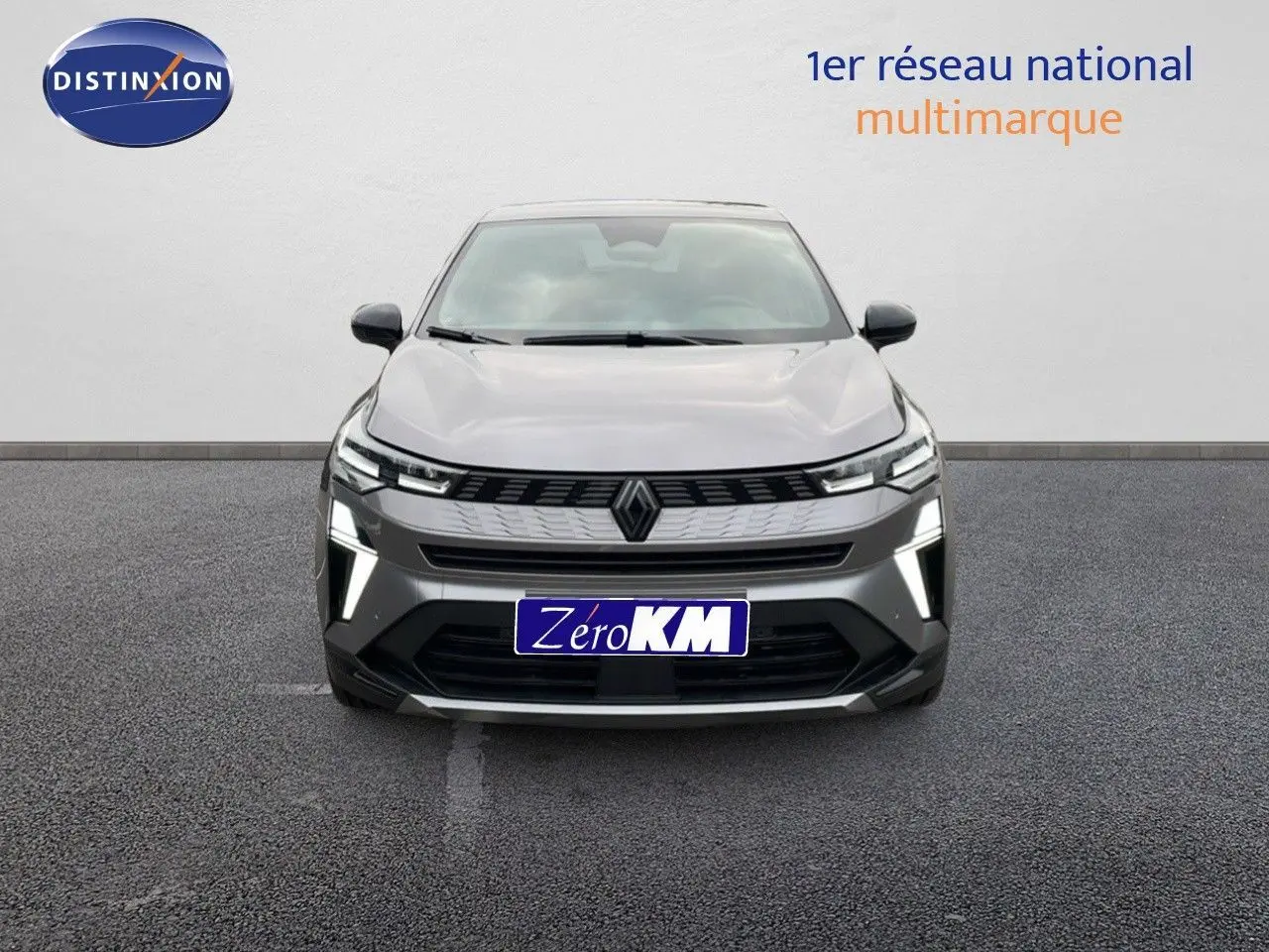 Vue frontale du Renault Symbioz gris cassiopée métal avec ses phares LED allumés sur fond neutre.
