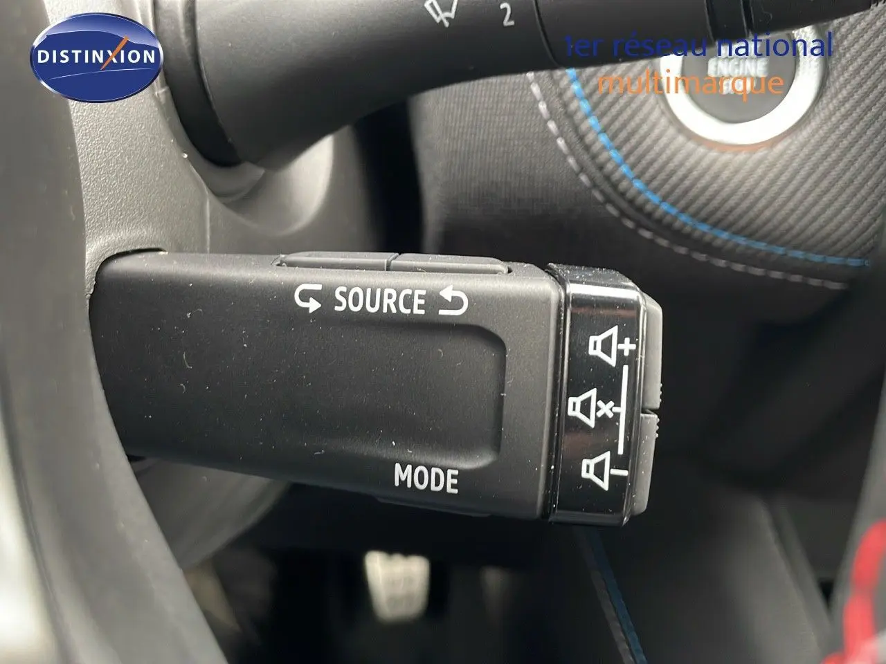 Gros plan sur la commande au volant du Renault Symbioz gris cassiopée, mettant en valeur les boutons source et mode.