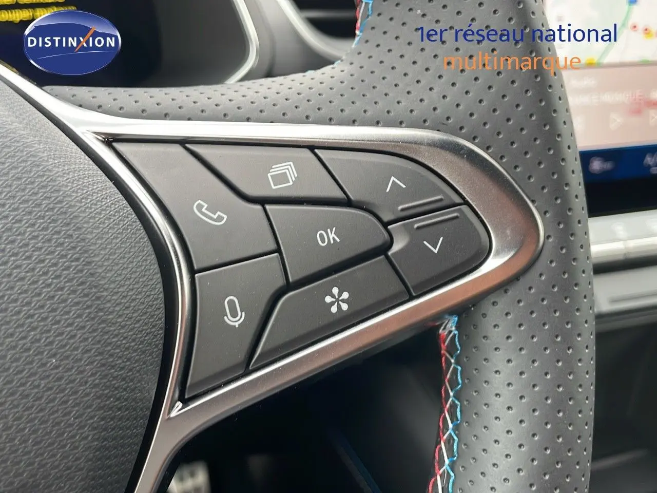 Gros plan sur les commandes du volant en cuir perforé noir avec surpiqûres tricolores du Renault Symbioz gris cassiopée métal.