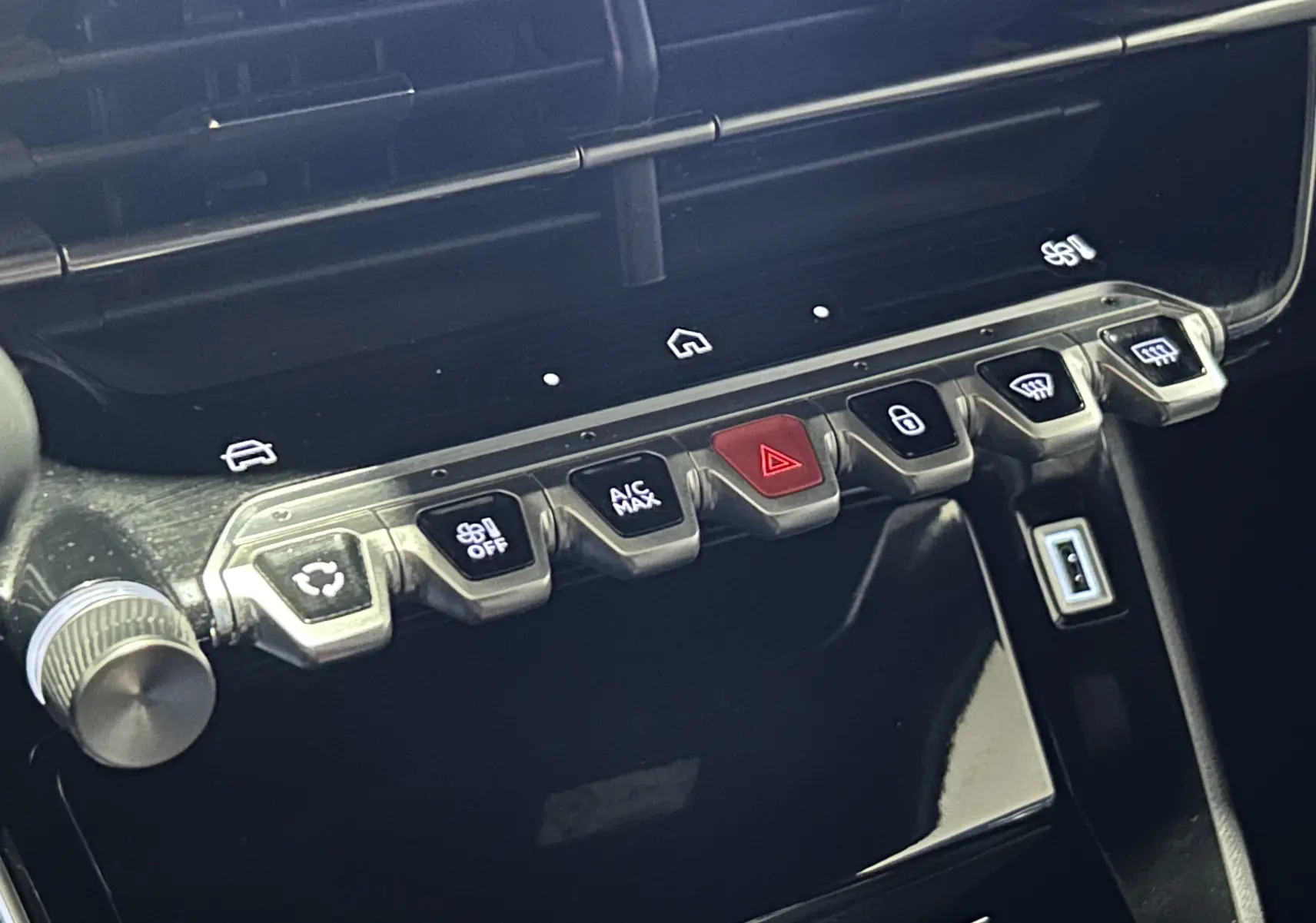 Gros plan sur la rangée de boutons de commande du tableau de bord du Peugeot 2008 II Ph.2 Allure Hybrid 145, finition noire brillante.