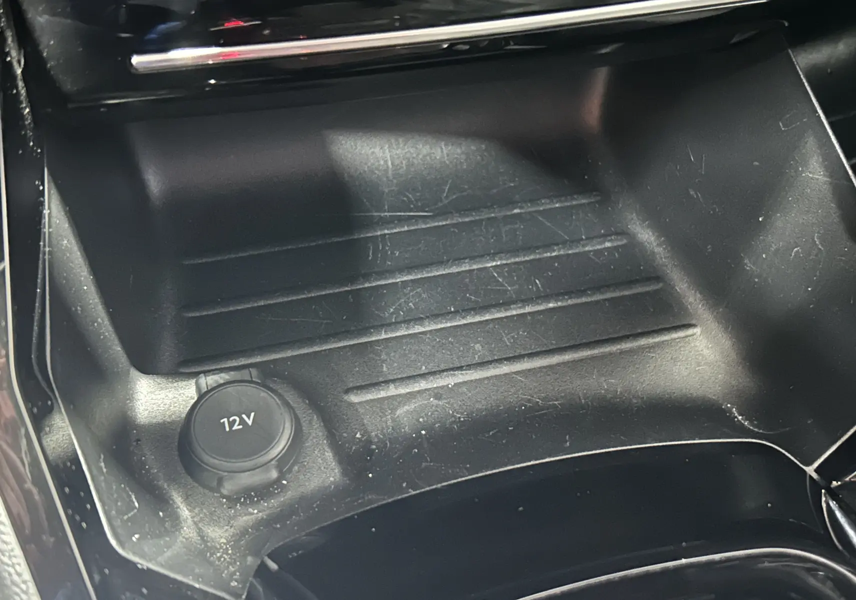 Prise 12V et espace de rangement dans la console centrale du Peugeot 2008 II Ph.2 Allure Hybrid 145, intérieur noir.