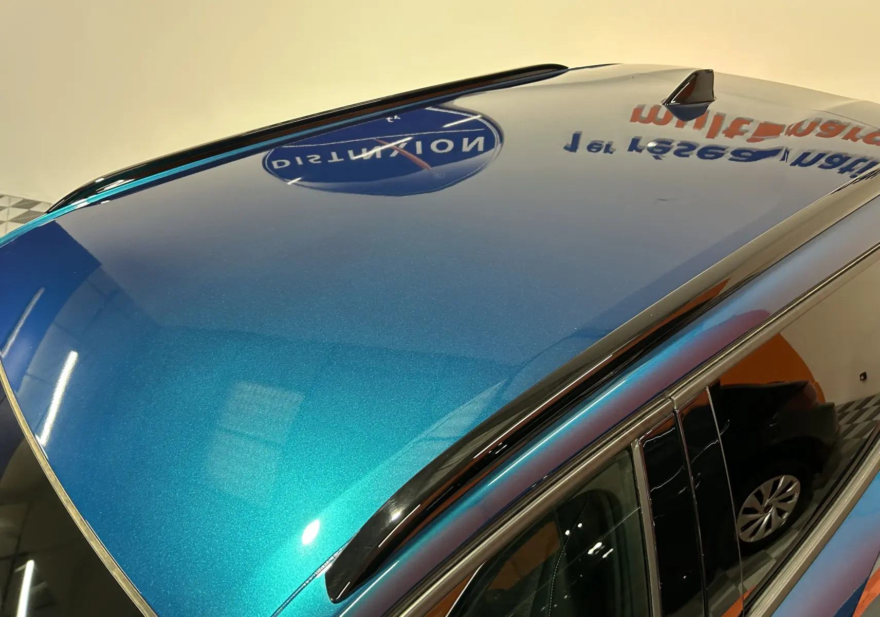 Toit bleu métallisé du Peugeot 2008 II Ph.2 Allure Hybrid 145 vu en plongée avec antenne requin et barres de toit noires.