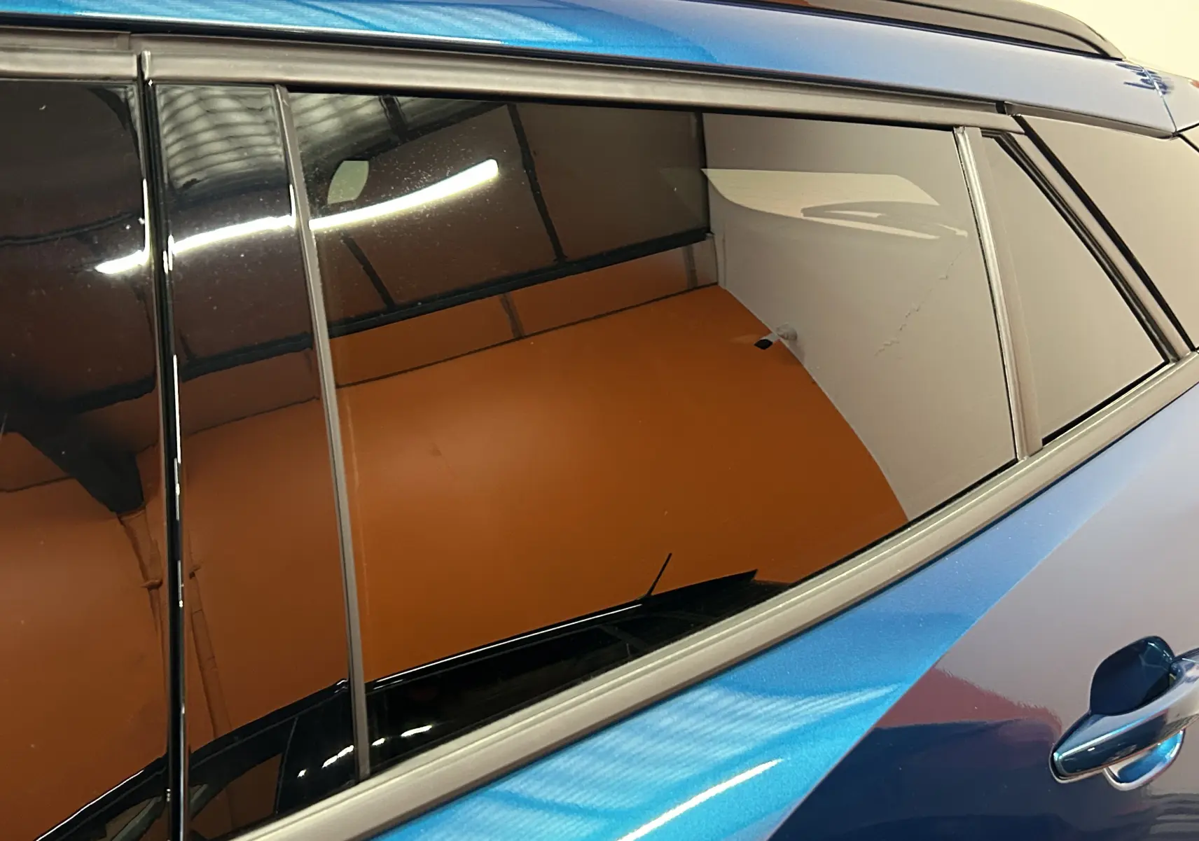 Vue rapprochée du côté gauche arrière d’une Peugeot 2008 Bleu Obsession avec vitres teintées et poignée de porte visible.