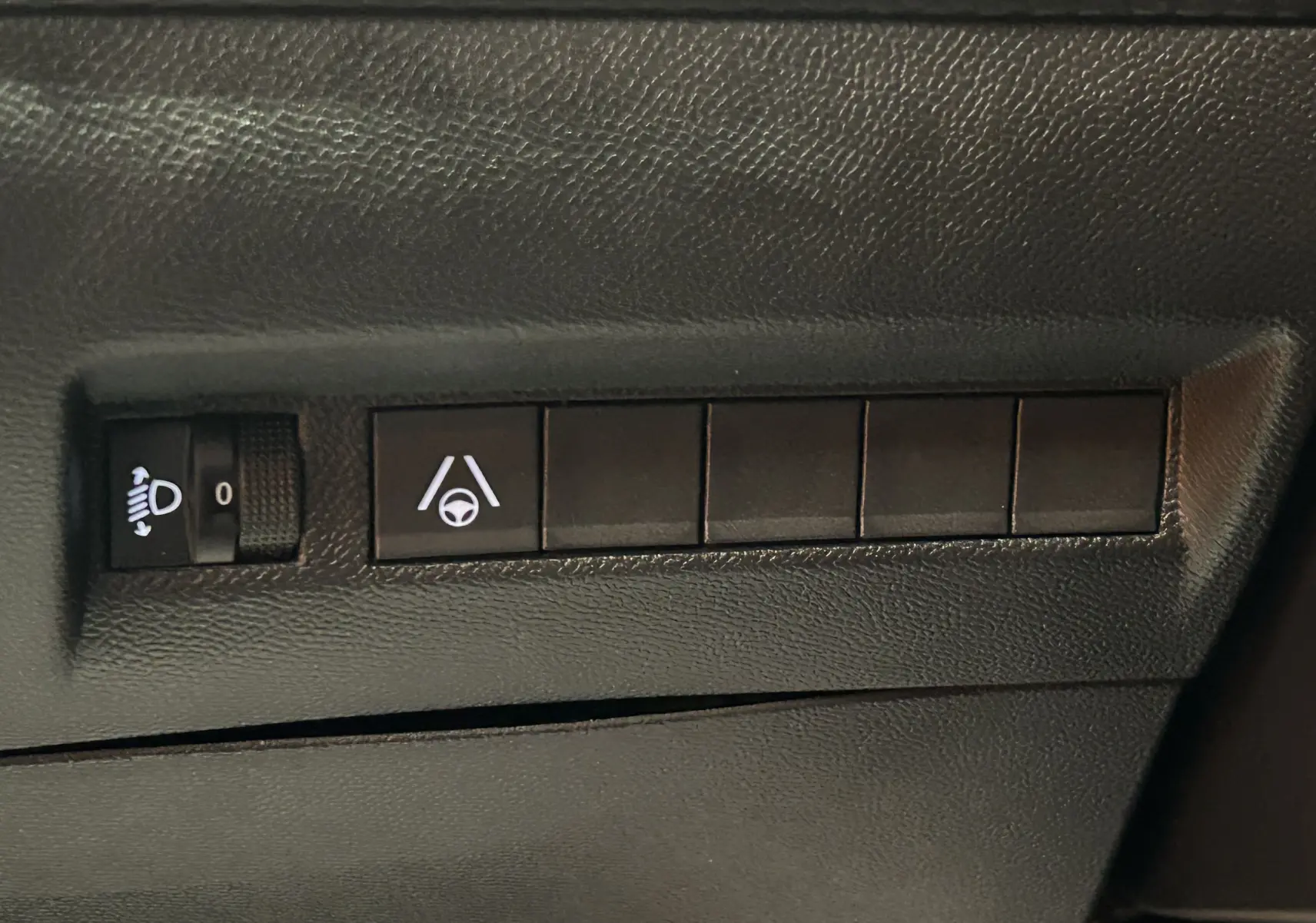 Gros plan sur les commandes de réglage des phares et d’aide au maintien de voie dans un Peugeot 2008 Bleu Obsession.