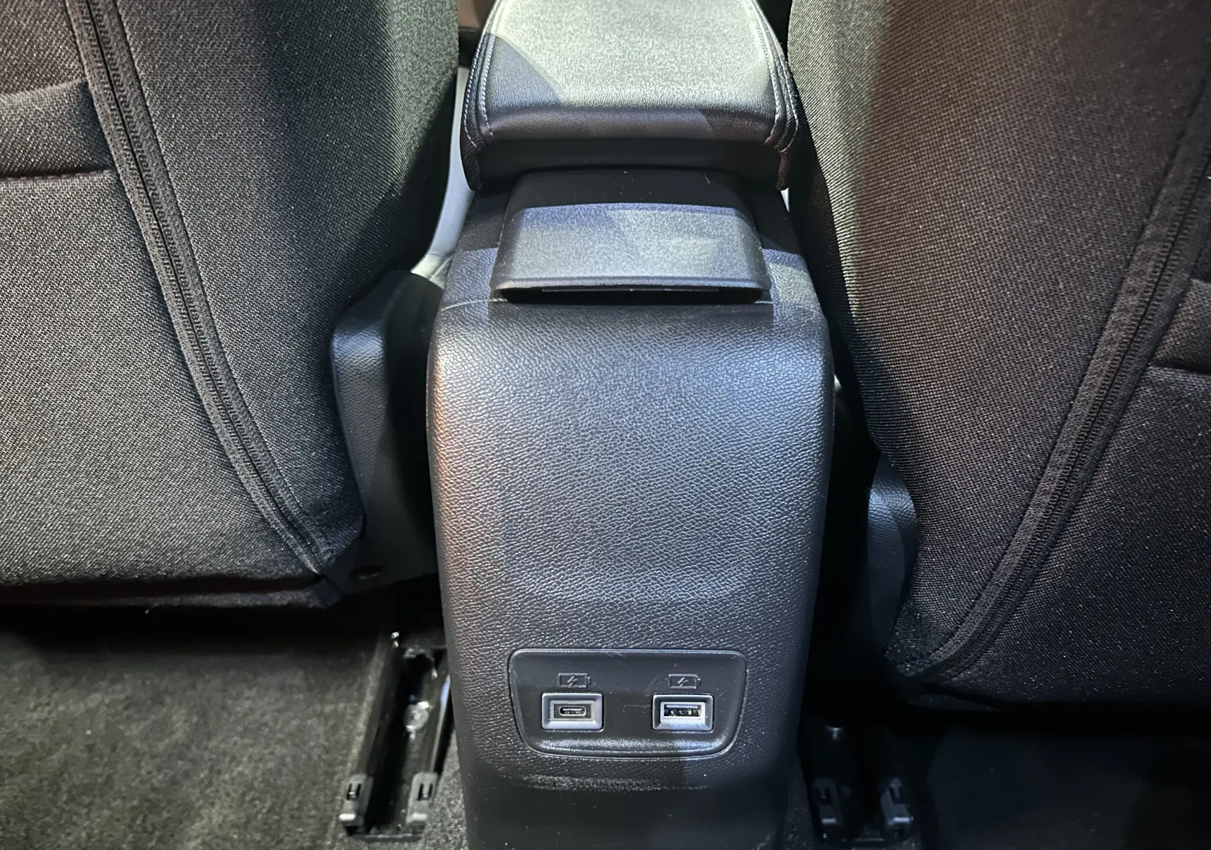 Prise USB double en bas de la console centrale arrière entre les sièges noirs du Peugeot 2008 bleu Obsession.