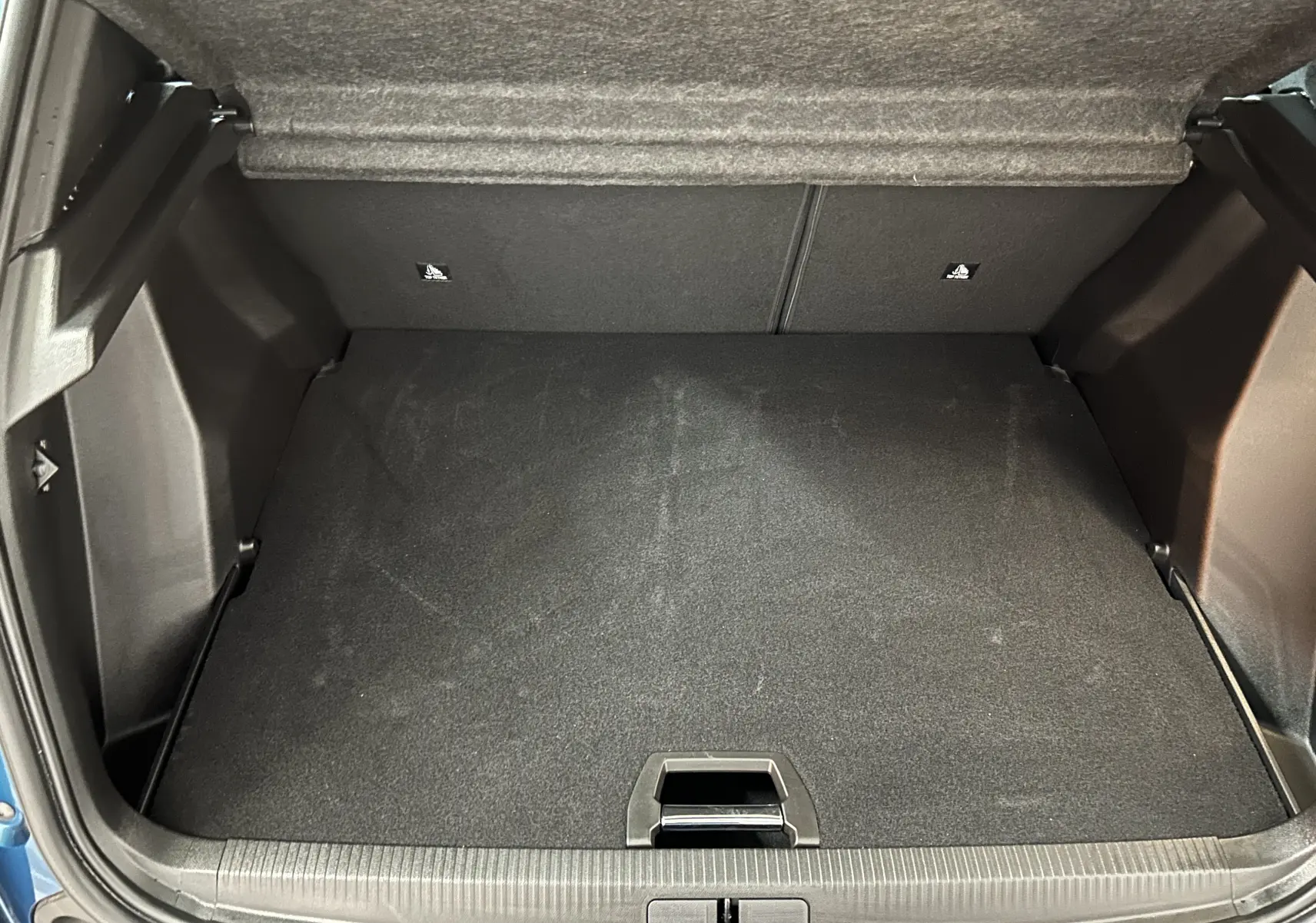 Coffre ouvert vu de face du Peugeot 2008 bleu Obsession, montrant l'espace de rangement vide et le plancher plat.