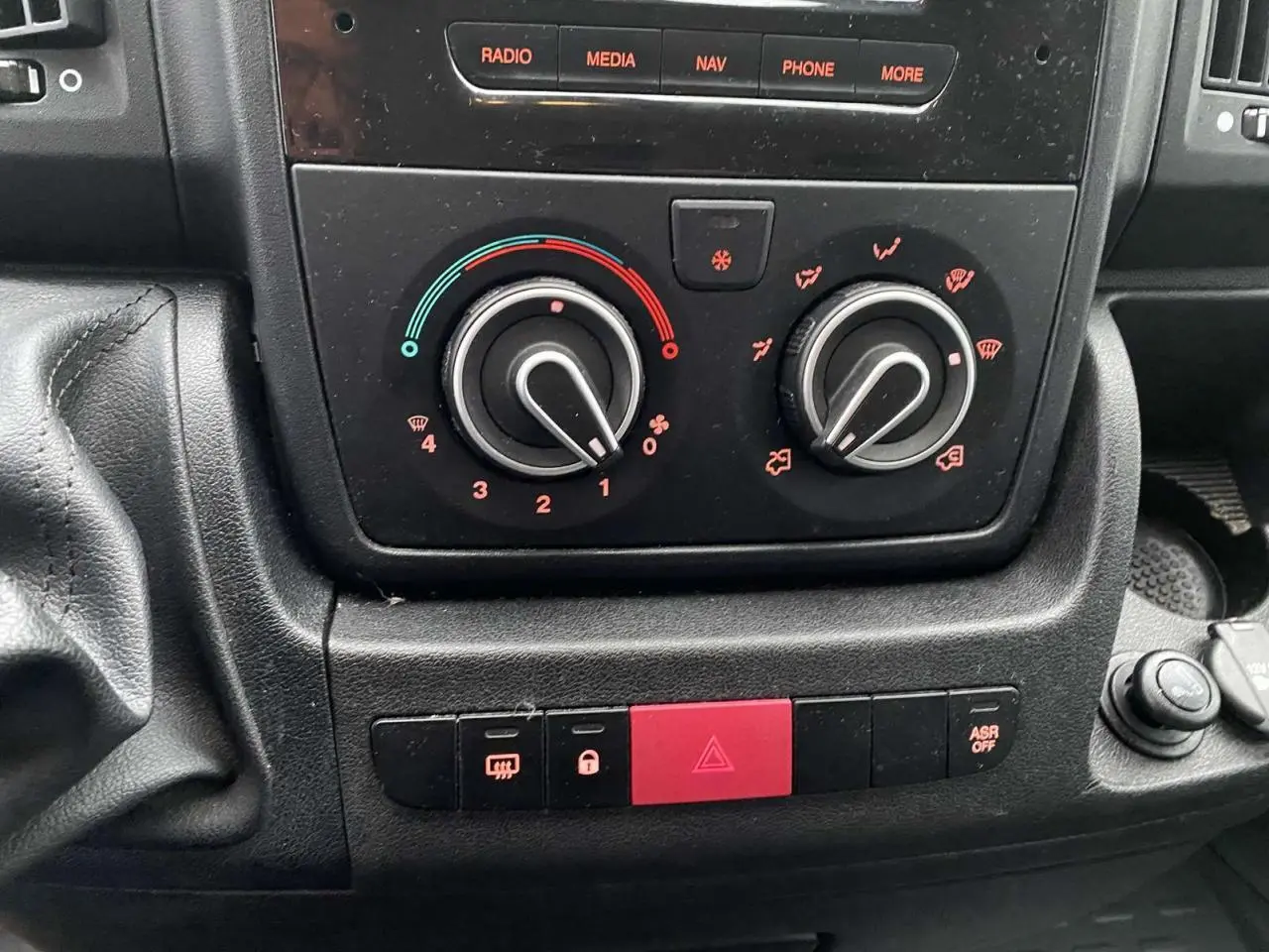 Vue rapprochée du tableau de bord de l'Opel Movano Fourgon 2022, montrant les commandes de climatisation et les boutons d'alerte.