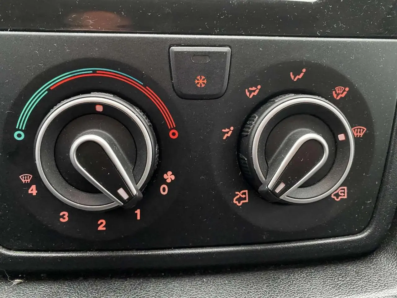 Gros plan sur les commandes de climatisation noires de l’Opel Movano Fourgon blanc, détails des réglages en rouge et bleu.
