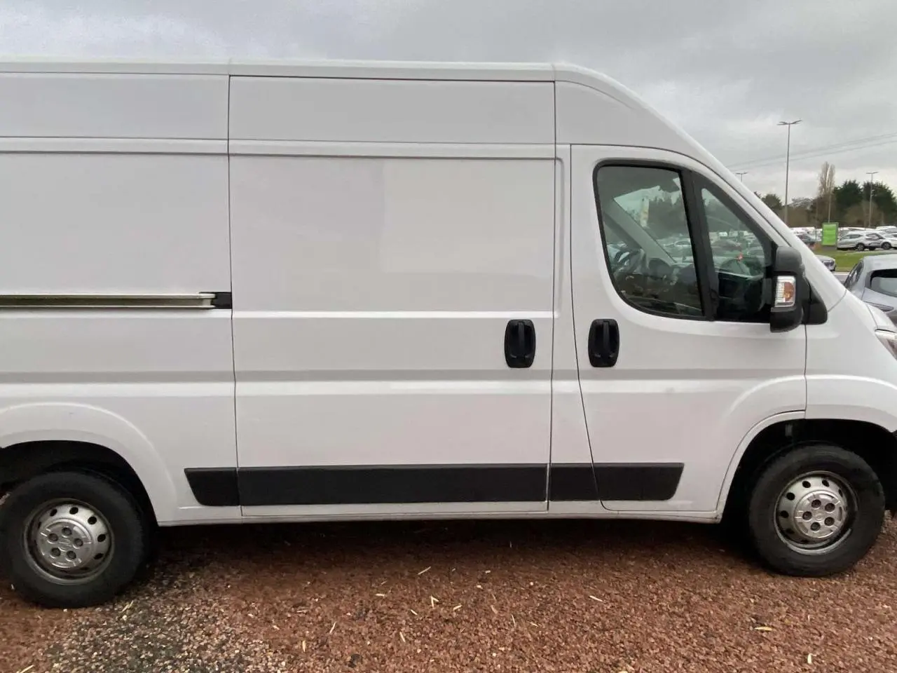Vue latérale droite d’un utilitaire blanc Opel Movano Fourgon 3.5T L2H2 avec portes coulissantes et protections noires.