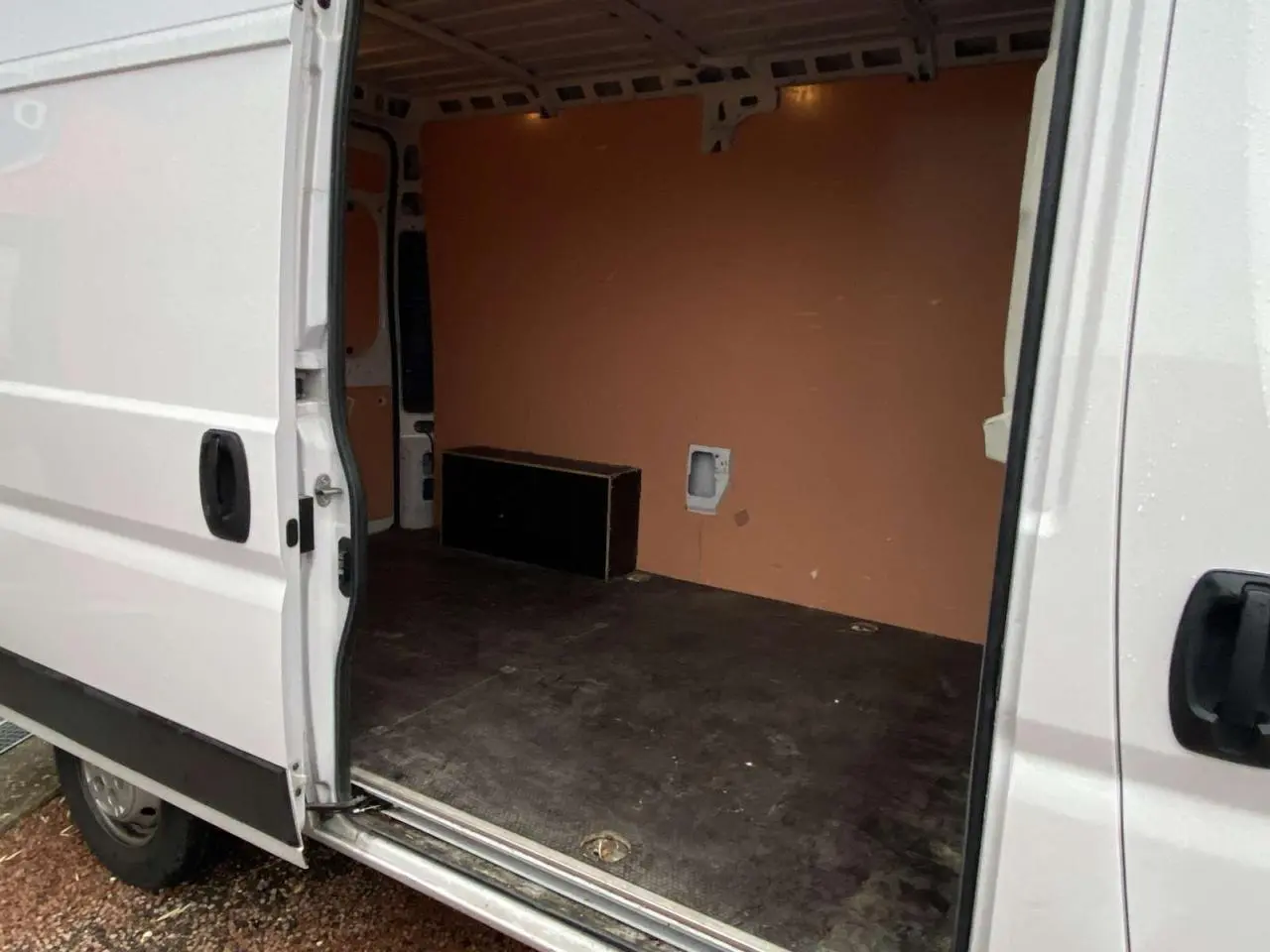 Vue latérale gauche du fourgon blanc Opel Movano 2022 avec porte coulissante ouverte montrant l’intérieur vide et plancher bois.