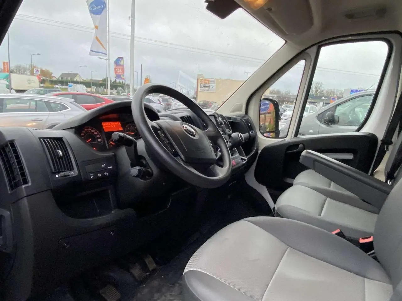 Vue intérieure côté conducteur de l’Opel Movano Fourgon blanc 2022, avec tableau de bord et sièges gris visibles.