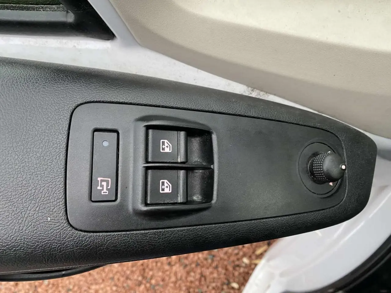 Gros plan sur les commandes de lève-vitres et réglage des rétroviseurs côté conducteur d’un Opel Movano blanc.