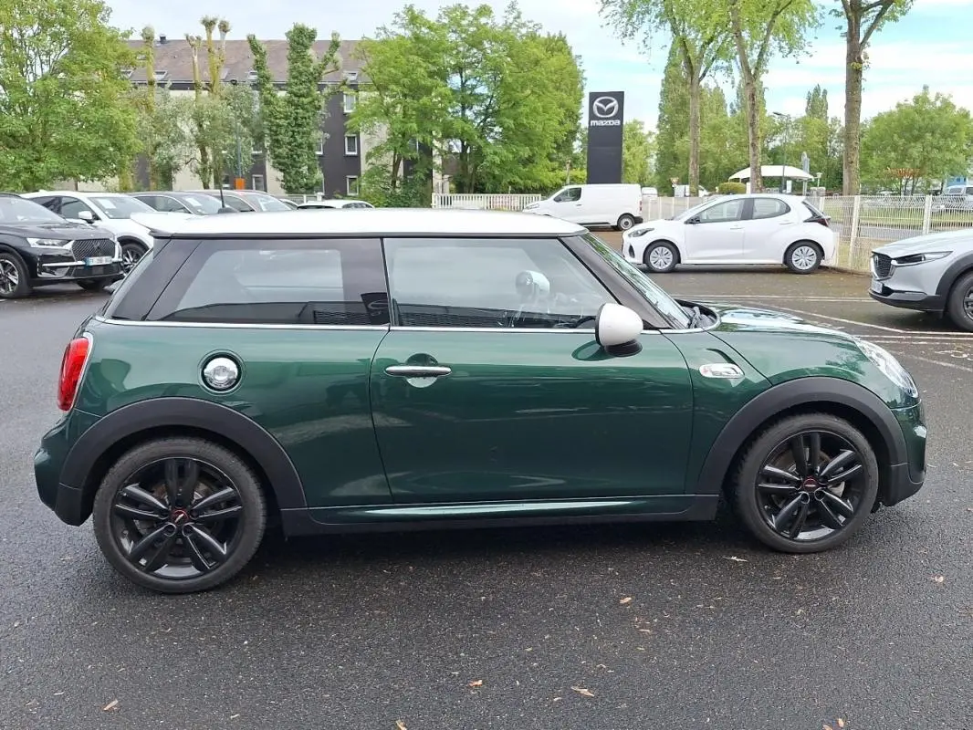 Vue de profil côté gauche d'une MINI S John Cooper Works 2015 vert foncé avec toit blanc et jantes noires.