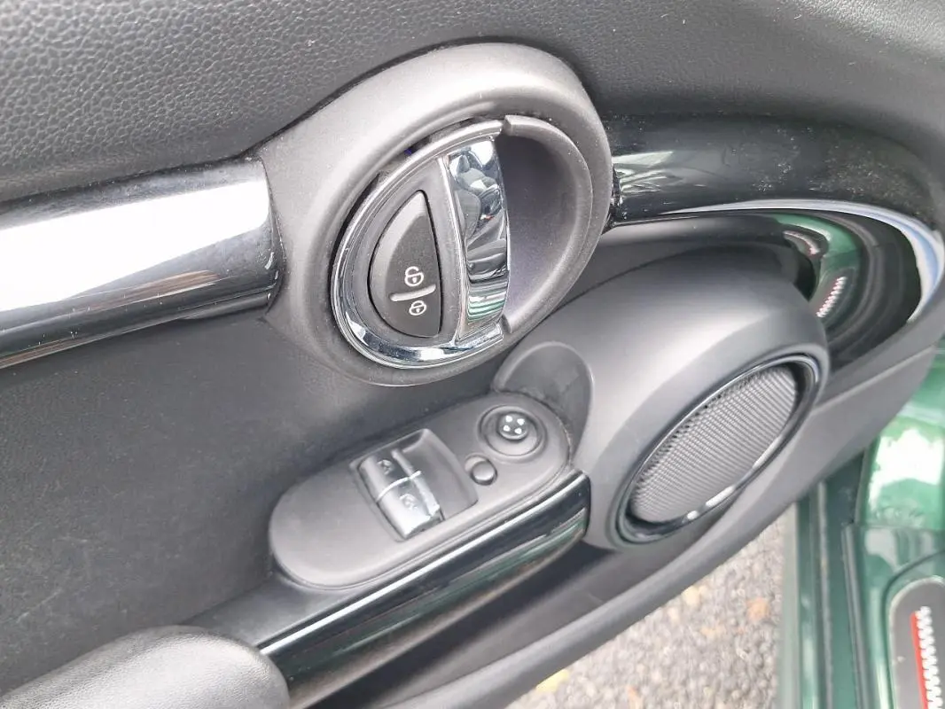Détail de la porte côté conducteur d'une MINI S John Work 2015 verte, montrant la poignée, les commandes de vitres et l'enceinte.