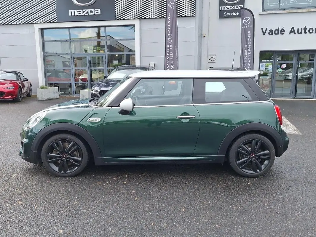 Vue de profil côté gauche d'une MINI S finition John Cooper Works 2015 verte avec toit blanc et jantes noires.