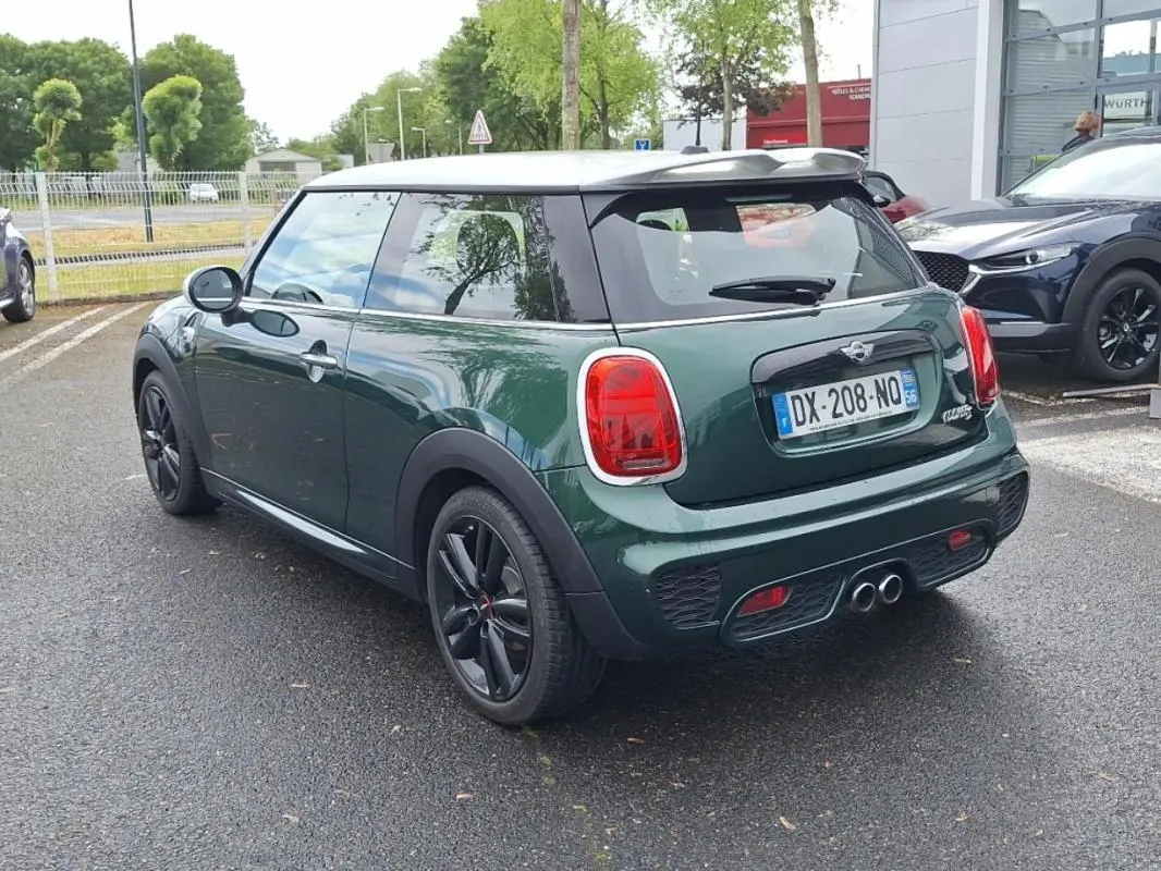 Vue 3/4 arrière droite d'une MINI S John Cooper Works 2015 vert foncé avec toit blanc et jantes noires.
